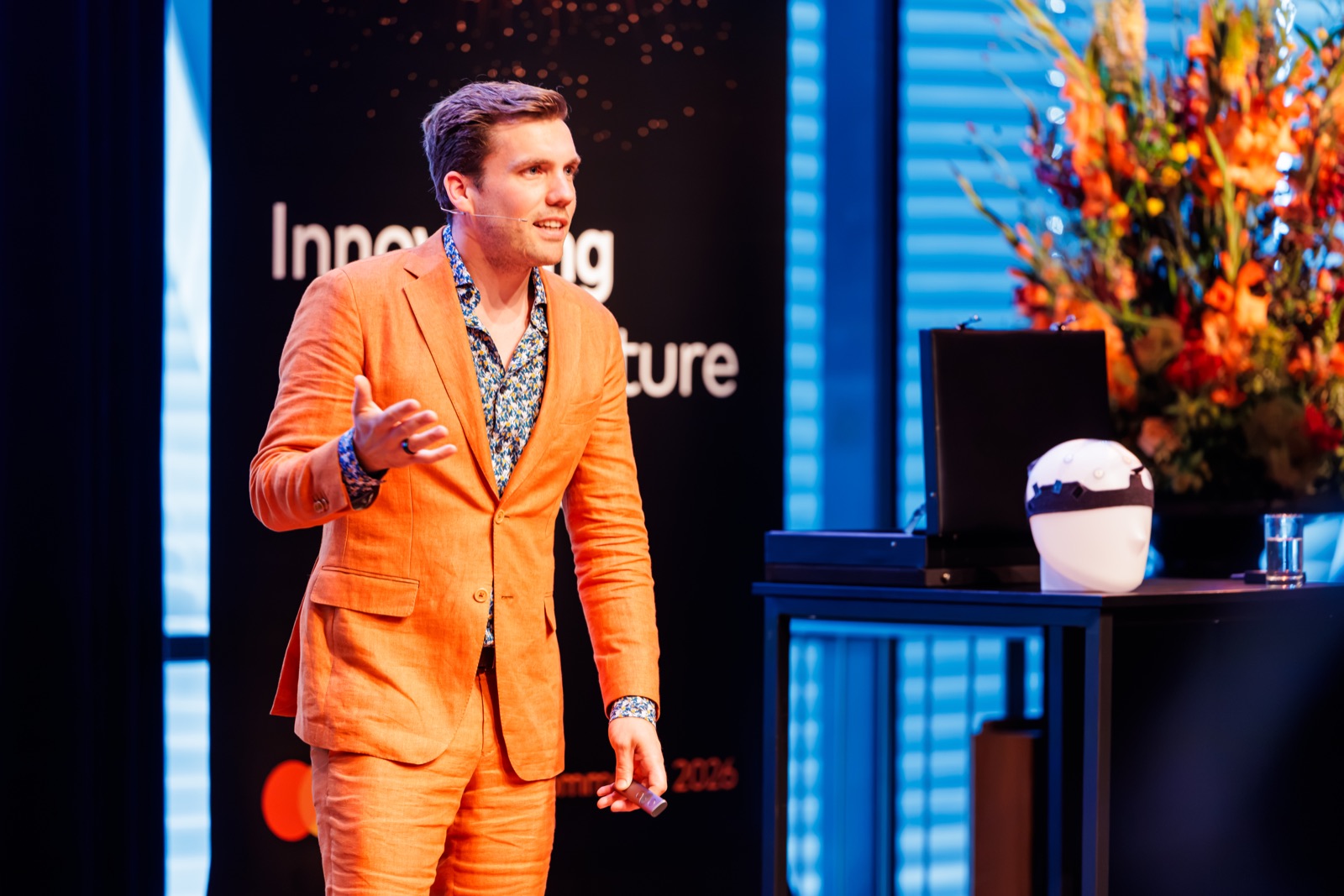 Tim Zuidgeest op het podium als AI-spreker, in zijn oranje pak